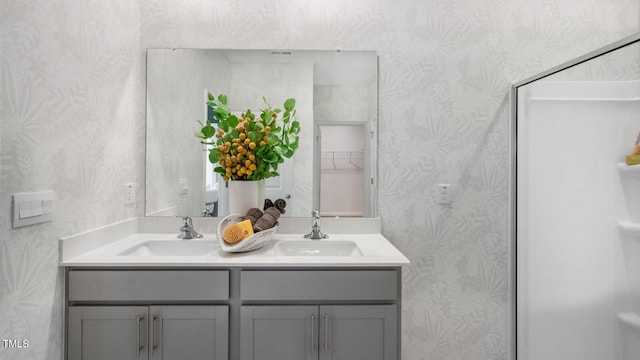 bathroom with double vanity, wallpapered walls, and a sink