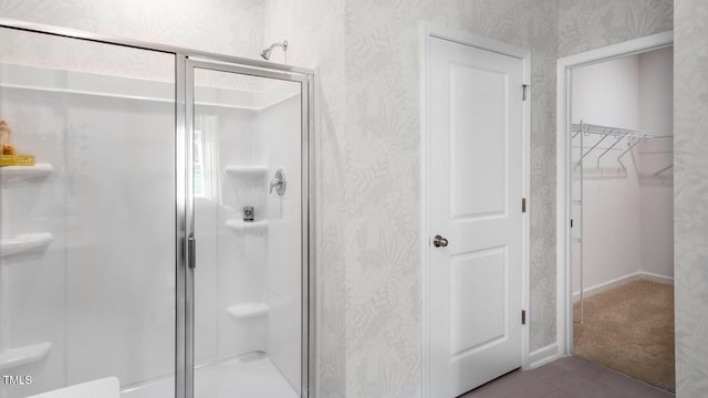 full bathroom featuring a stall shower, a walk in closet, and wallpapered walls