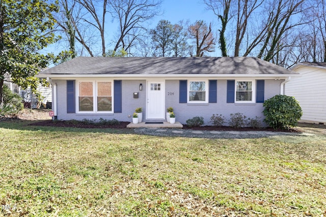 ranch-style home with brick siding, a front lawn, and roof with shingles