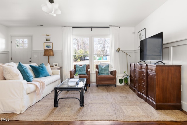 living area with a wealth of natural light, a wainscoted wall, and a decorative wall