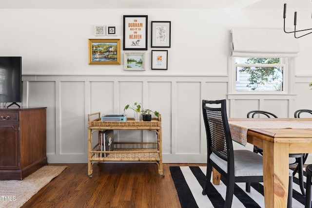 dining room featuring dark wood-style flooring and a decorative wall