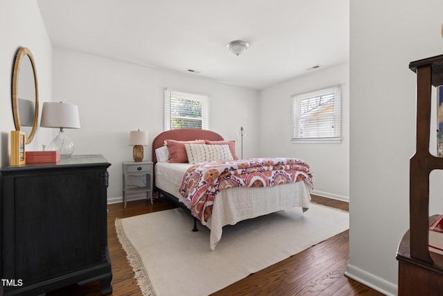 bedroom featuring dark wood-type flooring, multiple windows, visible vents, and baseboards