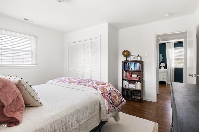 bedroom with visible vents, dark wood finished floors, and a closet