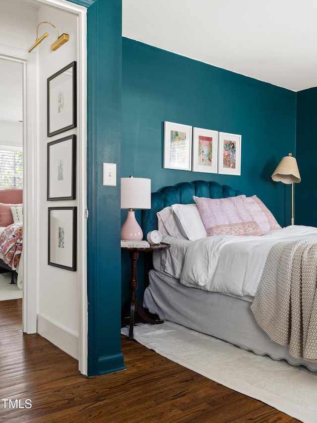 bedroom with dark wood finished floors and baseboards