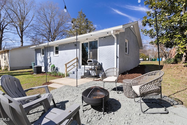 back of property with a patio, an outdoor fire pit, central AC unit, and brick siding