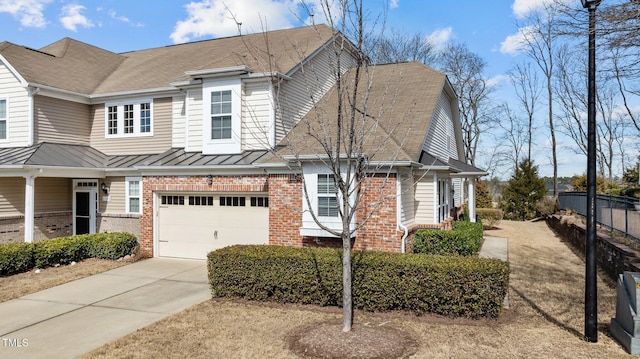 view of front of house featuring brick siding, concrete driveway, a standing seam roof, fence, and a garage