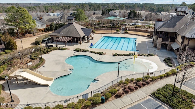 pool with a patio, a water slide, fence, a gazebo, and a residential view