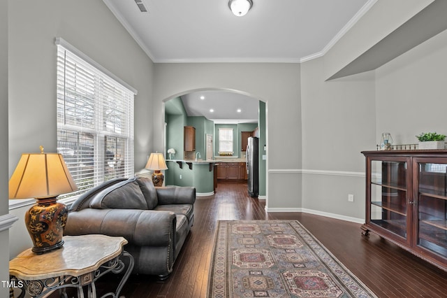 living room with ornamental molding, arched walkways, dark wood-style flooring, and baseboards