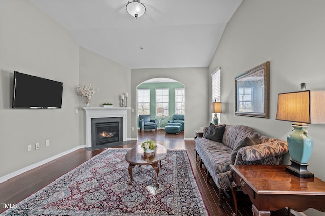 living room with a fireplace with flush hearth, baseboards, vaulted ceiling, and wood finished floors