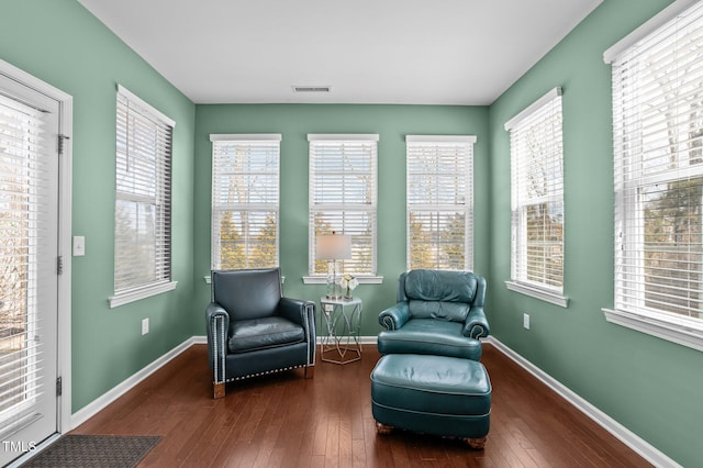 sitting room with wood-type flooring, visible vents, and baseboards