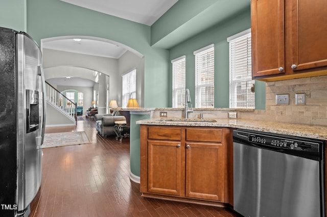 kitchen with a peninsula, appliances with stainless steel finishes, dark wood-style flooring, and a sink