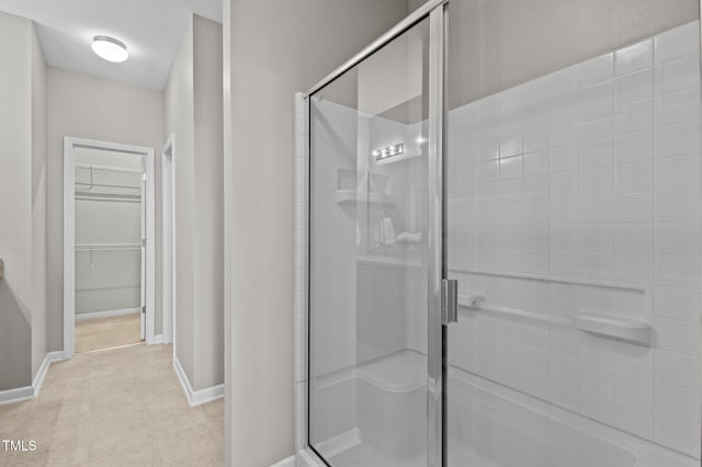 full bath with a stall shower, a spacious closet, and baseboards