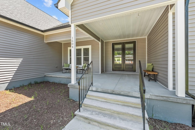 view of exterior entry featuring french doors, a porch, and a shingled roof