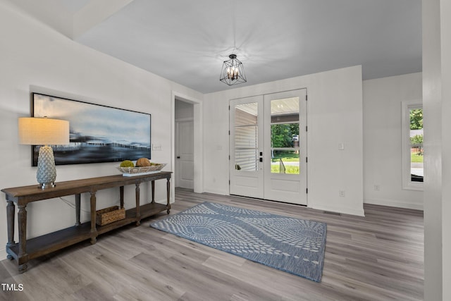 foyer with a notable chandelier, french doors, wood finished floors, and baseboards