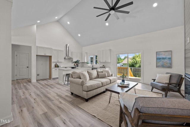 living room featuring light wood finished floors, baseboards, a ceiling fan, high vaulted ceiling, and recessed lighting