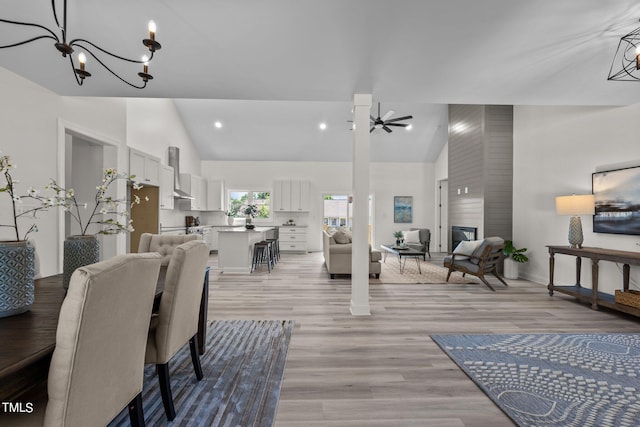 dining space with recessed lighting, high vaulted ceiling, light wood-type flooring, baseboards, and ceiling fan with notable chandelier