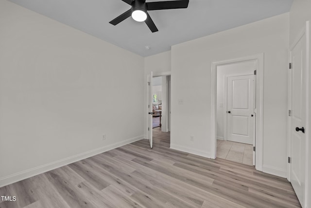 unfurnished bedroom with a ceiling fan, light wood-style flooring, and baseboards