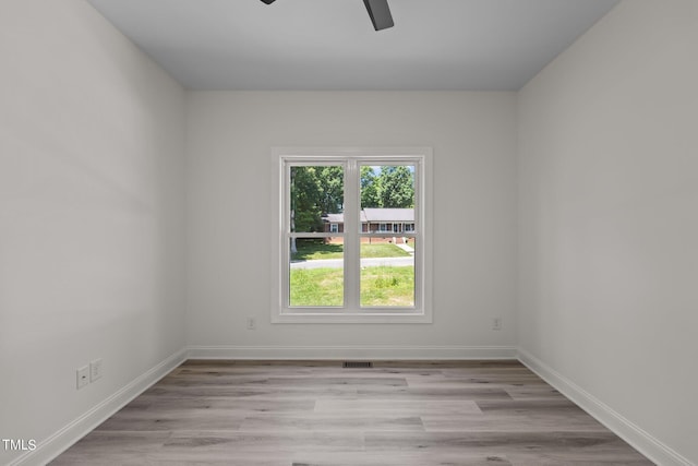 empty room featuring visible vents, wood finished floors, a ceiling fan, and baseboards