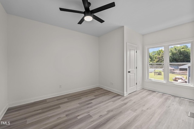 spare room featuring light wood-style floors, visible vents, baseboards, and a ceiling fan