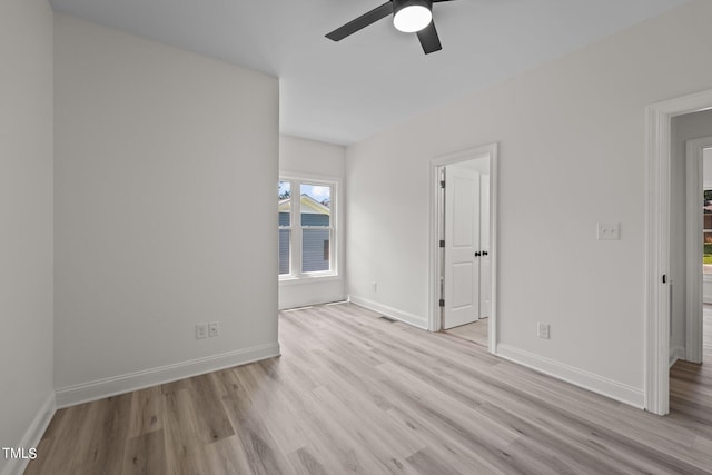 spare room with a ceiling fan, visible vents, baseboards, and wood finished floors