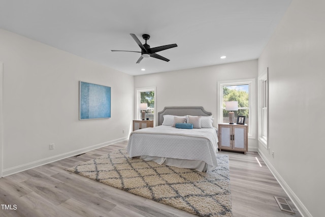 bedroom featuring light wood-style flooring, multiple windows, visible vents, and baseboards