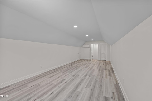 additional living space with light wood finished floors, lofted ceiling, recessed lighting, a wall mounted air conditioner, and baseboards