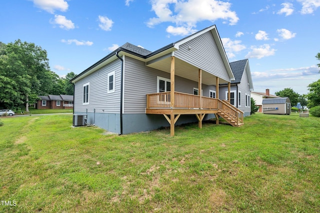 rear view of house featuring a deck, central AC unit, a lawn, and a shingled roof