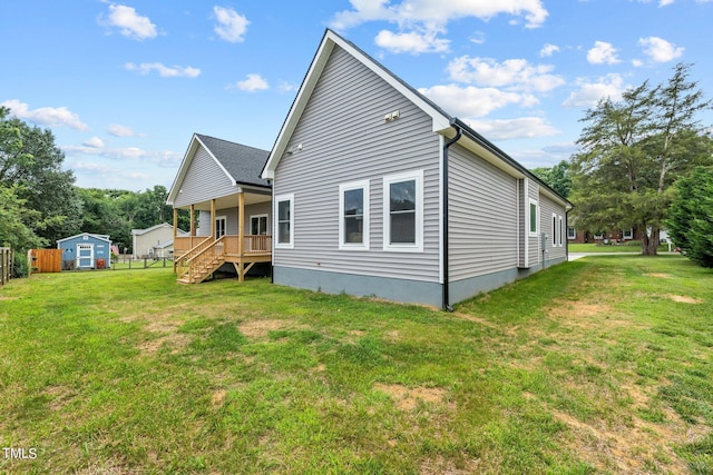 rear view of property featuring a storage unit, a lawn, an outdoor structure, and fence