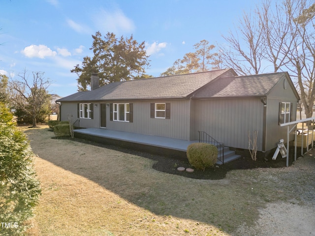 rear view of property featuring a chimney and roof with shingles