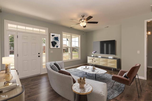 living area with baseboards, plenty of natural light, a ceiling fan, and dark wood-style floors