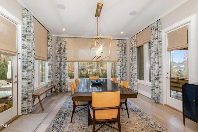 dining area featuring light wood-style floors, ornamental molding, and a notable chandelier