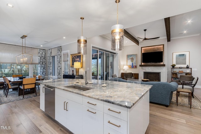 kitchen featuring stainless steel dishwasher, light stone counters, light wood-style floors, and a sink