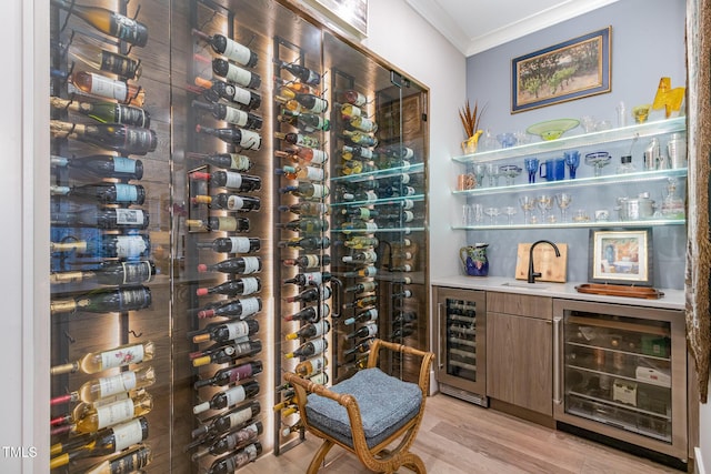 wine area with a sink, wine cooler, light wood-style floors, and crown molding