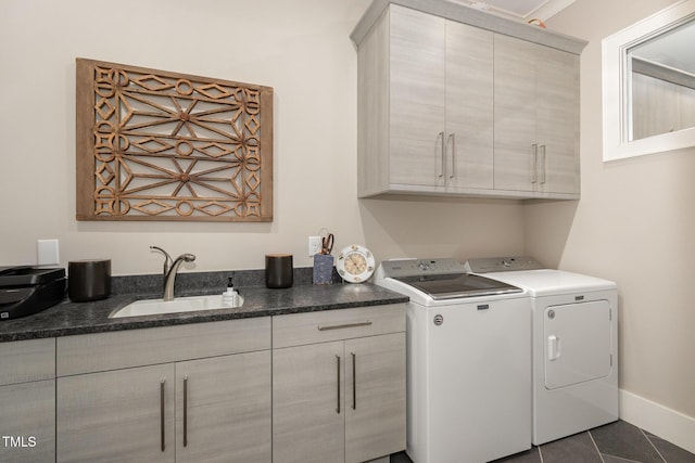 laundry room featuring cabinet space, baseboards, washer and clothes dryer, dark tile patterned flooring, and a sink