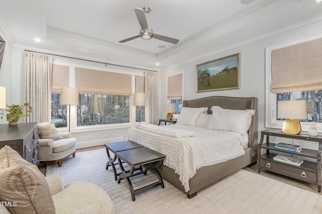 bedroom with ceiling fan, wood finished floors, a raised ceiling, and crown molding