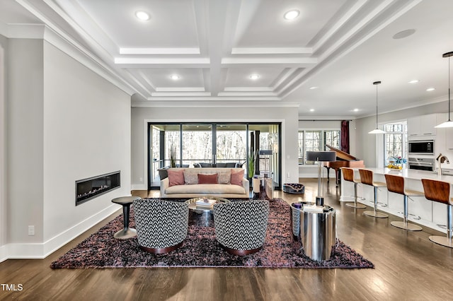 living room featuring crown molding, dark wood finished floors, a glass covered fireplace, coffered ceiling, and baseboards