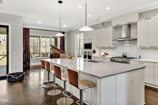 kitchen featuring decorative backsplash, wall chimney exhaust hood, ornamental molding, built in microwave, and a sink