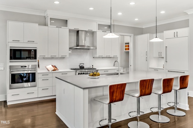 kitchen featuring dark wood-style floors, ornamental molding, a sink, wall chimney range hood, and oven