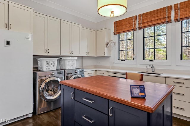 washroom with washing machine and dryer, dark wood-type flooring, a sink, ornamental molding, and cabinet space