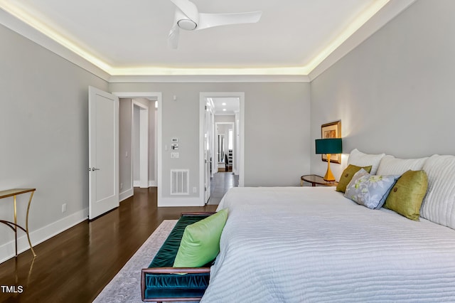 bedroom with a ceiling fan, visible vents, baseboards, and wood finished floors