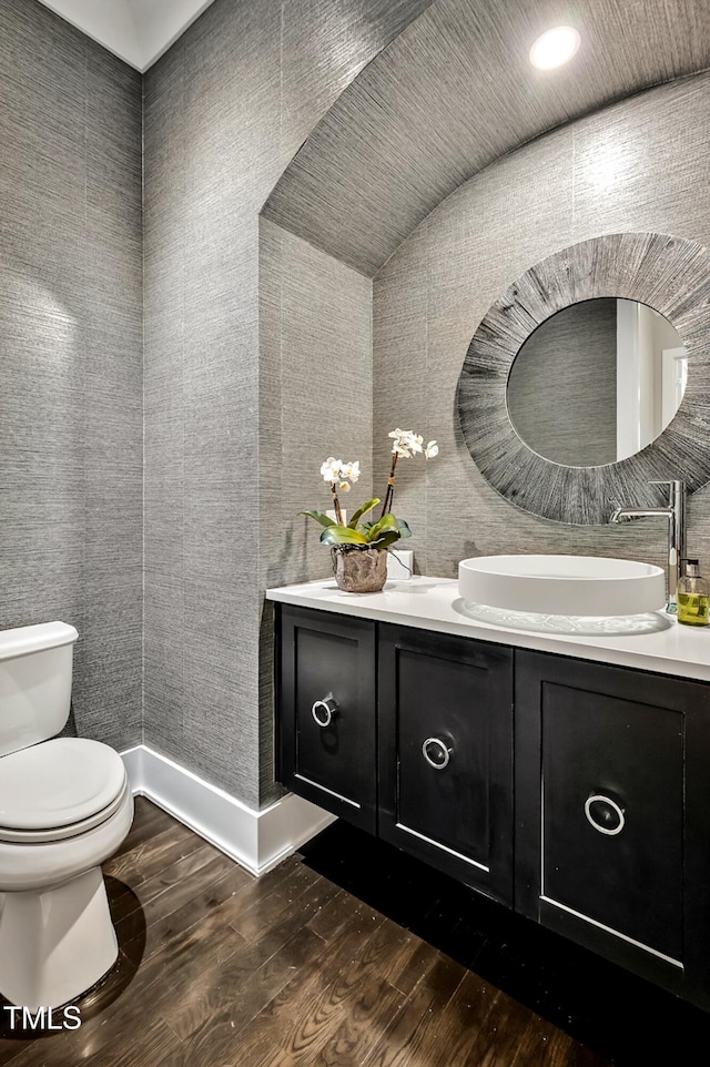 bathroom with toilet, baseboards, wood finished floors, and vanity