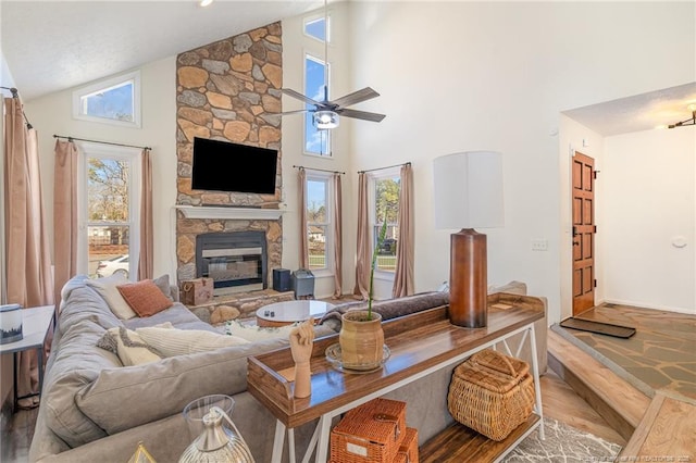 living area featuring high vaulted ceiling, a fireplace, wood finished floors, and a ceiling fan