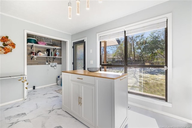 clothes washing area with marble finish floor, ornamental molding, and baseboards