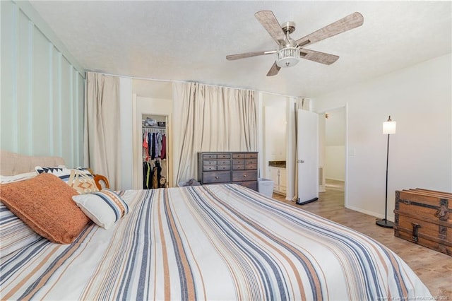 bedroom with a ceiling fan, a closet, light wood-style flooring, and a spacious closet