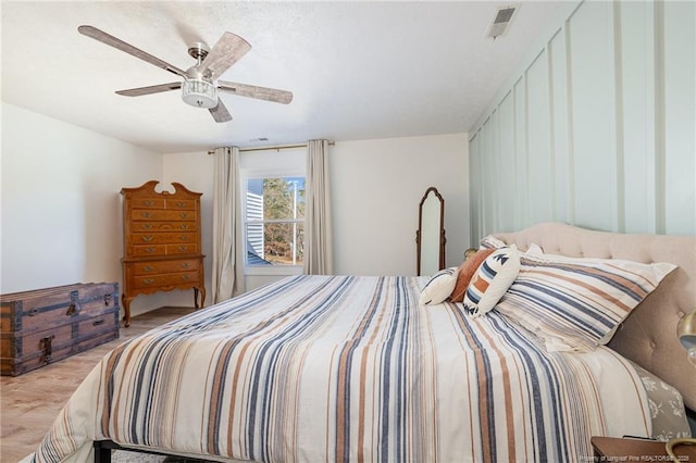 bedroom featuring a ceiling fan, visible vents, and wood finished floors