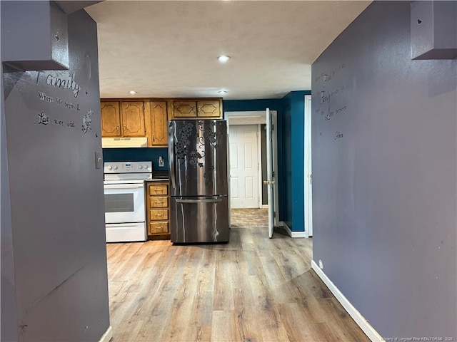 kitchen with brown cabinets, white electric stove, light wood-style floors, freestanding refrigerator, and under cabinet range hood