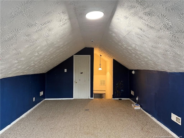 additional living space featuring lofted ceiling, carpet, visible vents, and a textured ceiling