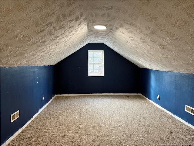 bonus room with carpet, visible vents, vaulted ceiling, a textured ceiling, and baseboards