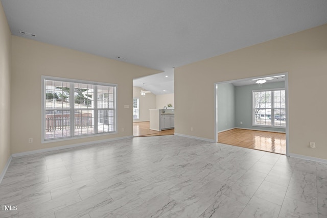 unfurnished living room featuring marble finish floor, a sink, visible vents, and baseboards