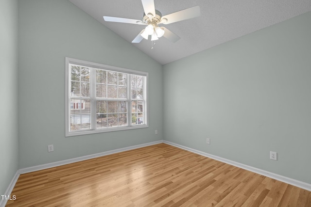 spare room featuring vaulted ceiling, light wood-type flooring, and baseboards